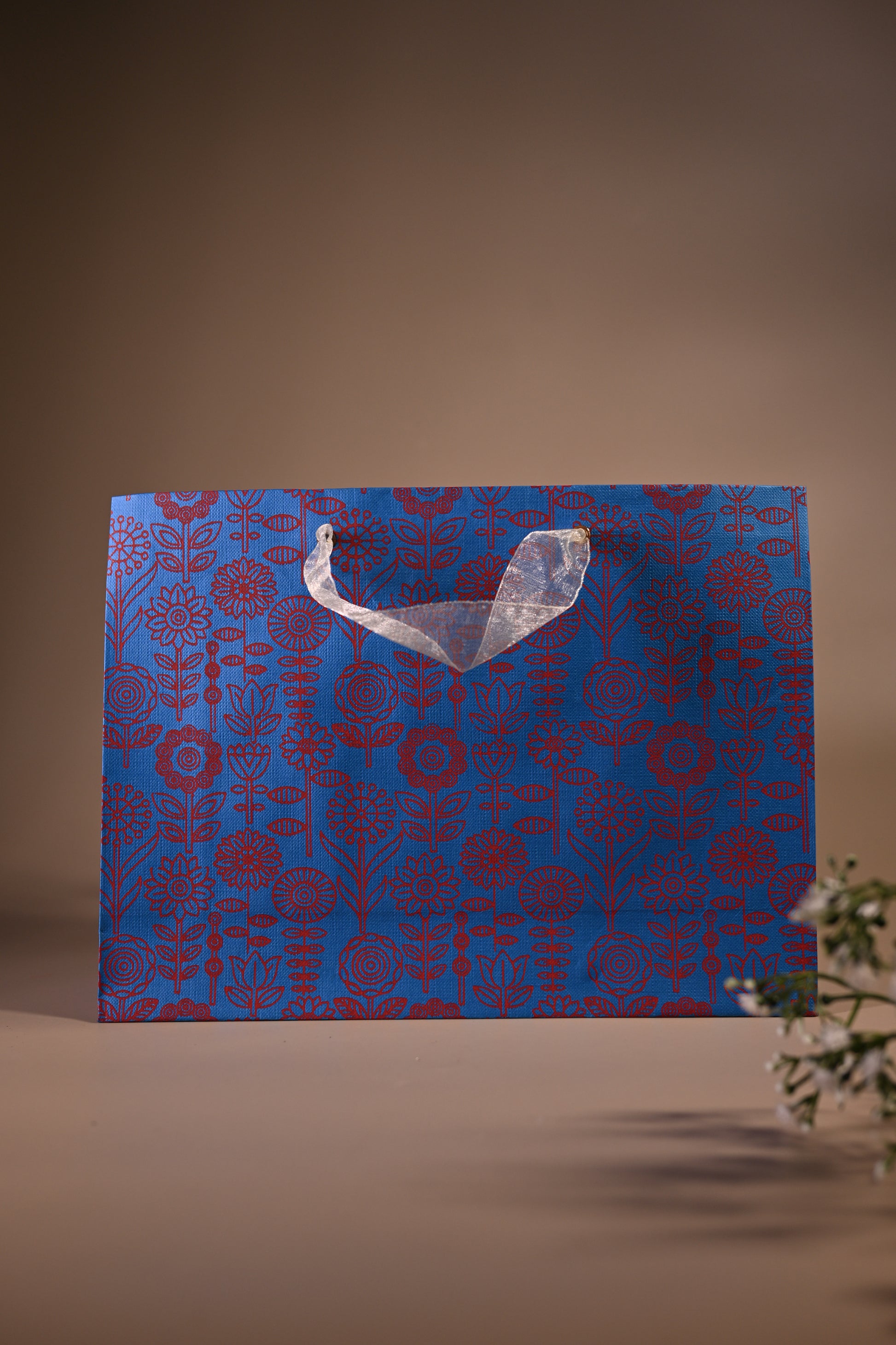 blue bag with ribbon handle and red flower motif