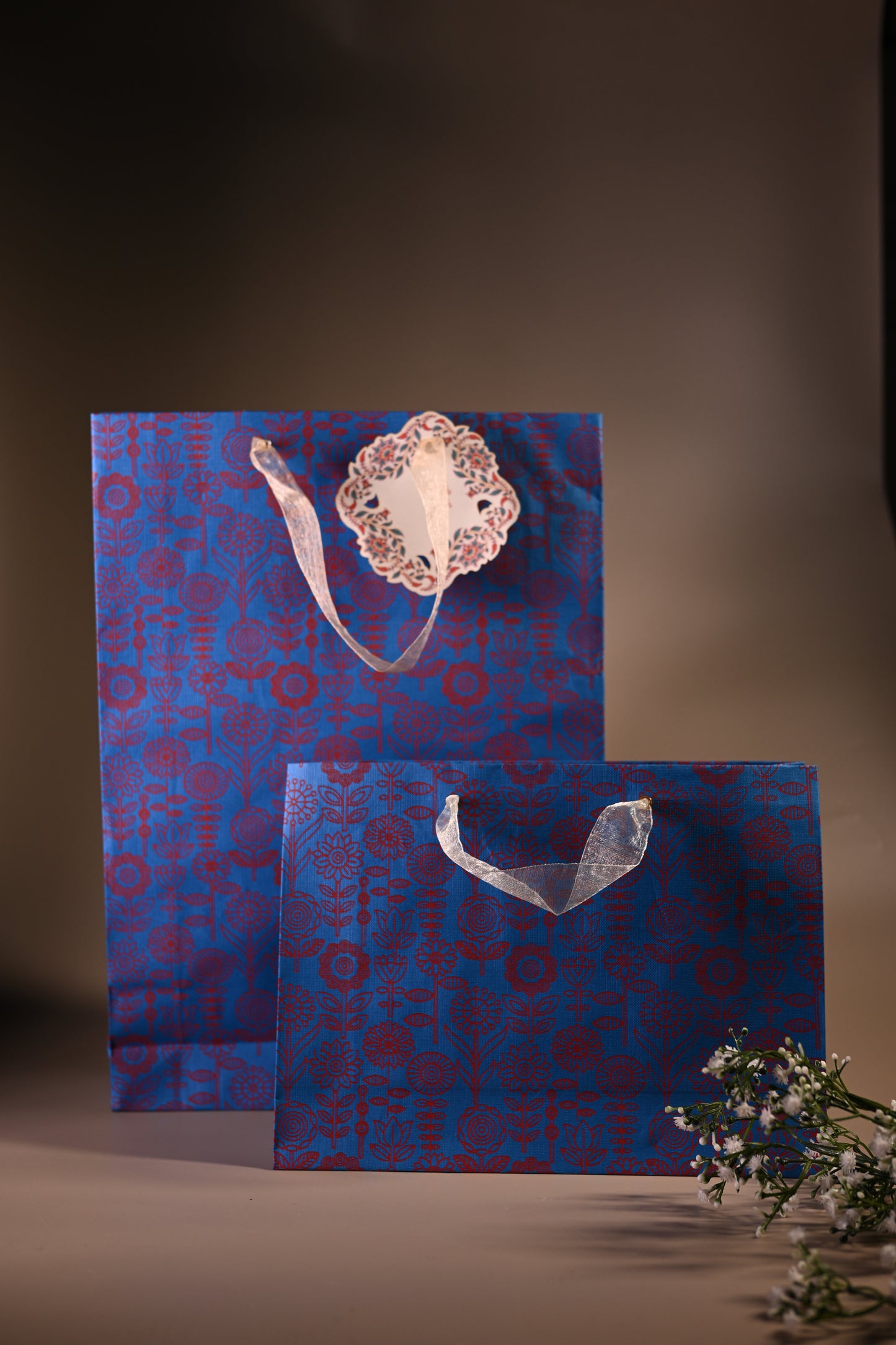 blue bag with ribbon handle and red flower motif