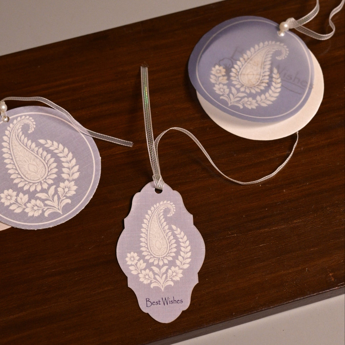 A set of decorative paper tags with white paisley design on a light purple background.