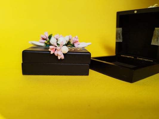 A brown coin box with a floral design, featuring a secure magnetic lock and adorned with artificial flowers.