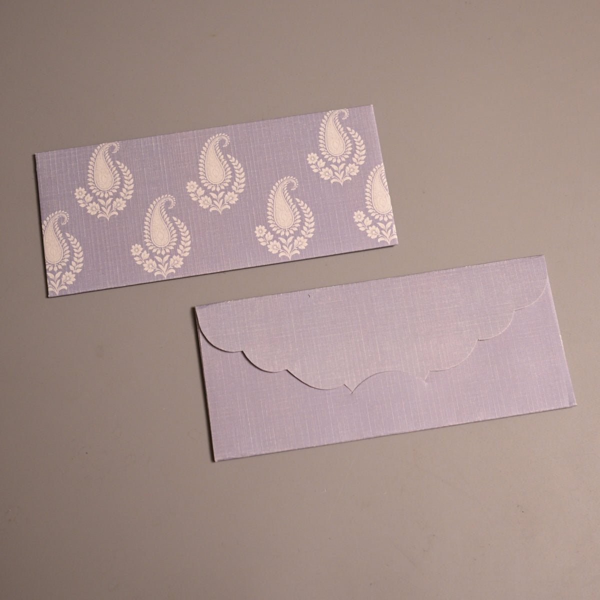 avender paper, one with a white paisley pattern and the other with a scalloped envelope flap