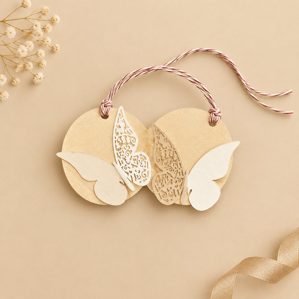 A round off-white metallic paper gift tag with a ribbon handle and laser-cut butterflies design