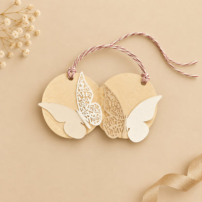 A round off-white metallic paper gift tag with a ribbon handle and laser-cut butterflies design