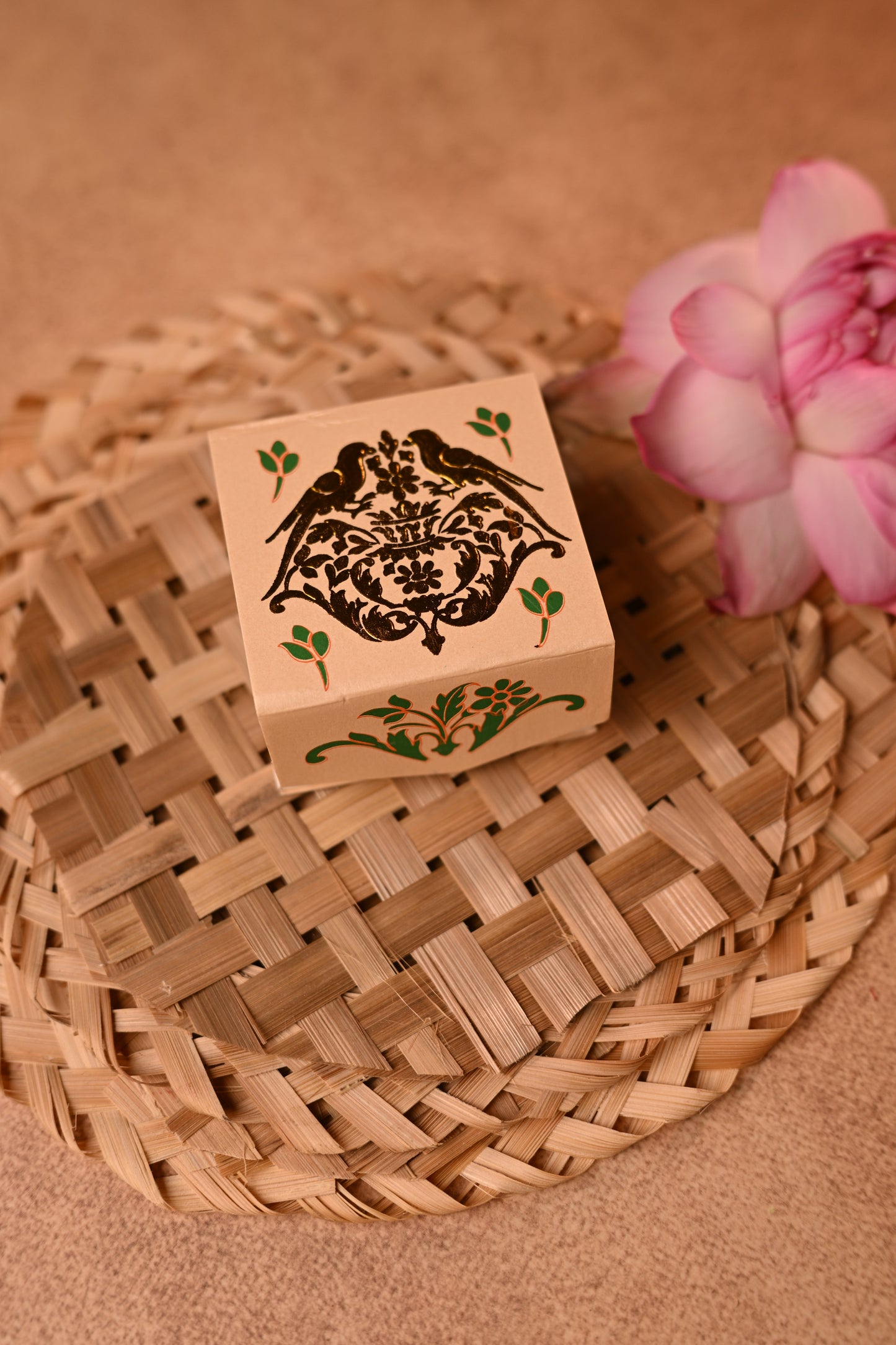 A beige cardboard coin box with a foil embossed parrot motif