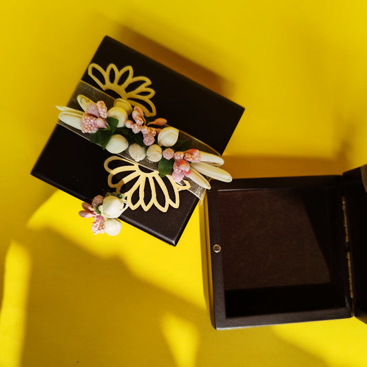 A brown coin box with a floral design, featuring a secure magnetic lock and adorned with artificial flowers.