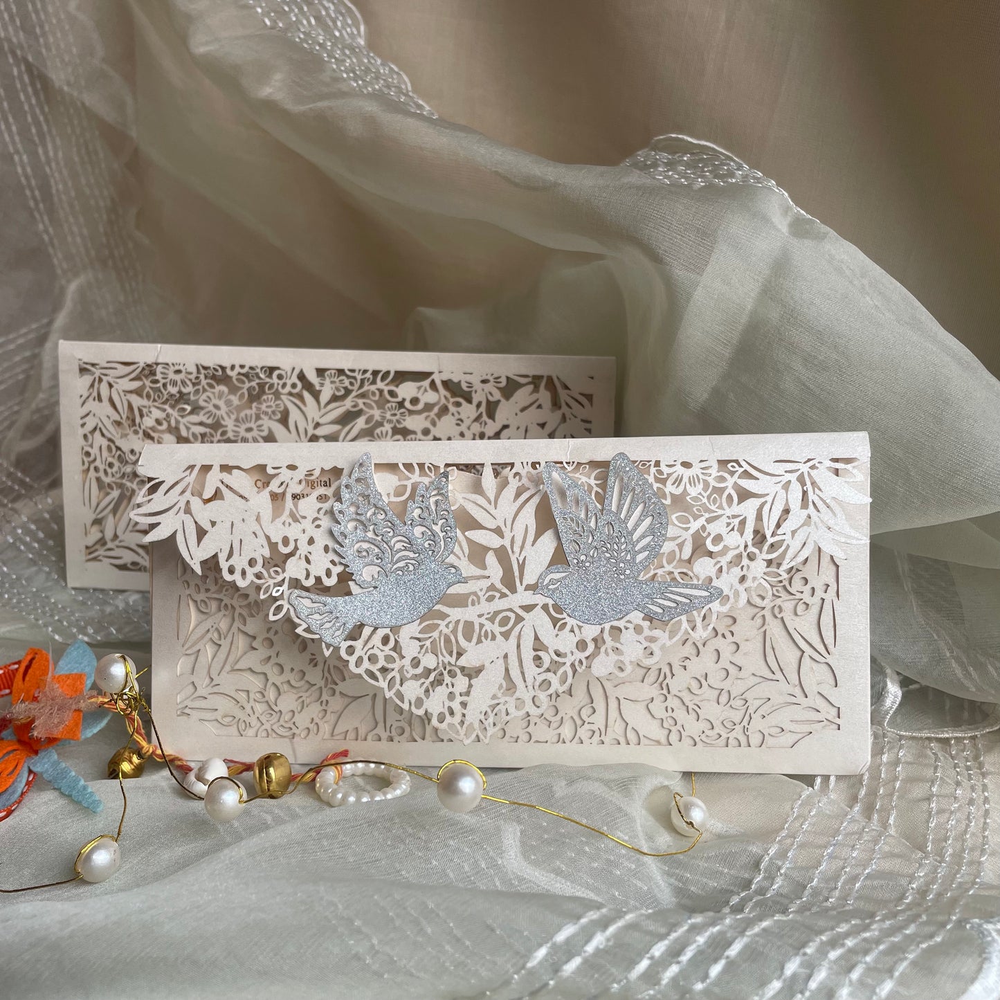 Decorative off white Envelope with intricate cut-out designs on an ivory metallic paper. Pair of birds pasted on its flap.