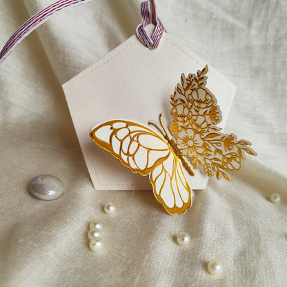A set of white gift tags with gold foil-embossed butterfly designs, tied with a ribbon.