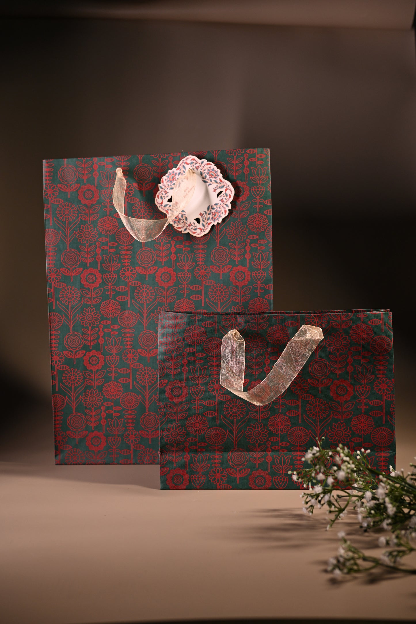 green paper bag with red floral motifs and ribbon handle