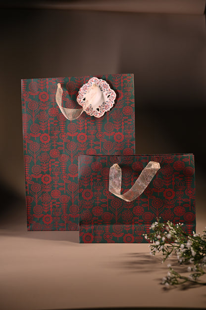 green paper bag with red floral motifs and ribbon handle