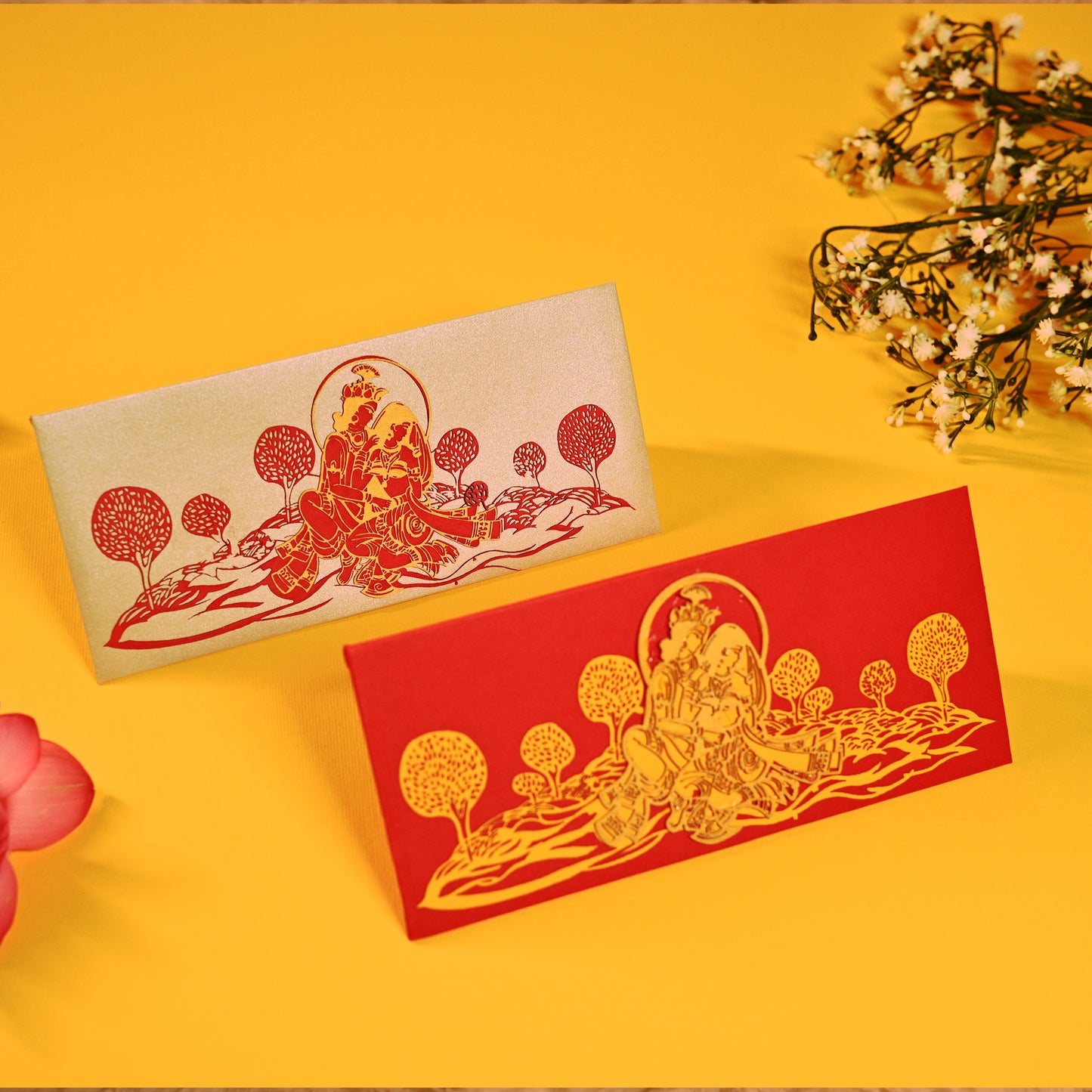 A set of laser-cut money envelopes with a Radha Krishna motif, in red, gold, and silver colours