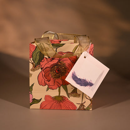 Floral gift box with a card and feather on a brown background