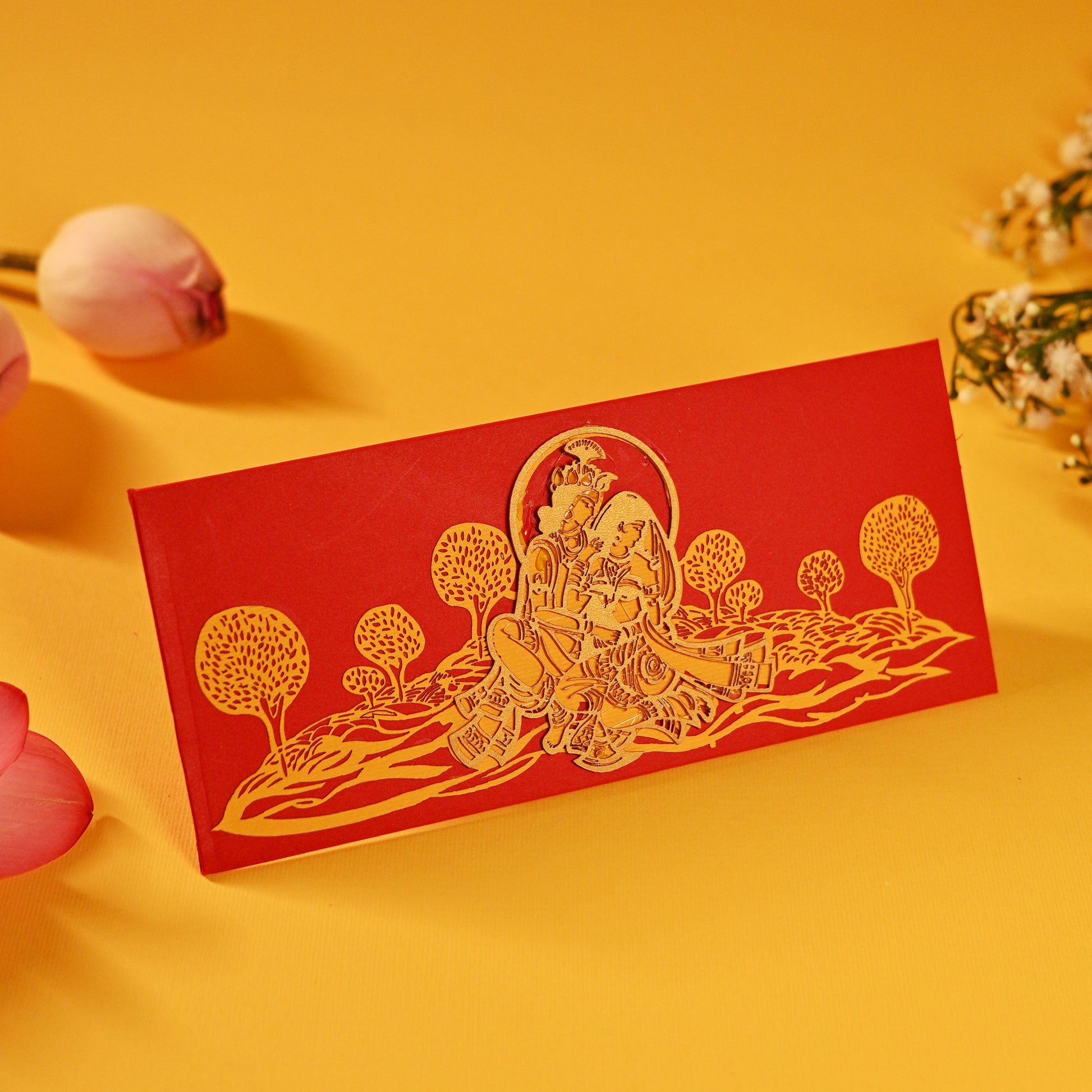 A set of laser-cut money envelopes with a Radha Krishna motif, in red, gold, and silver colours