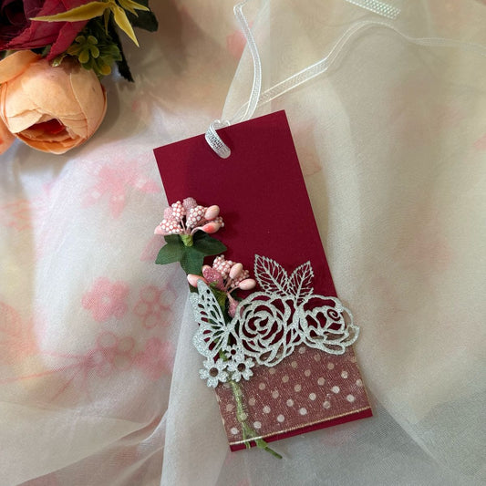 red gift tag with white ribbon and floral designs