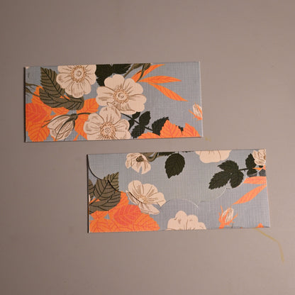 Envelope with floral pattern in orange, cream, and dark green on a light gray background