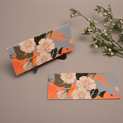 Sagun Envelope with a floral pattern in orange, beige, and green on a gray background