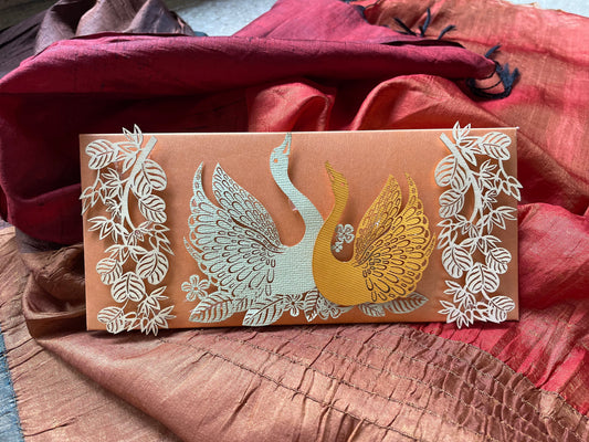 laser cut swan design in the centre on a brown envelope with leaves and floral pattern on the sides