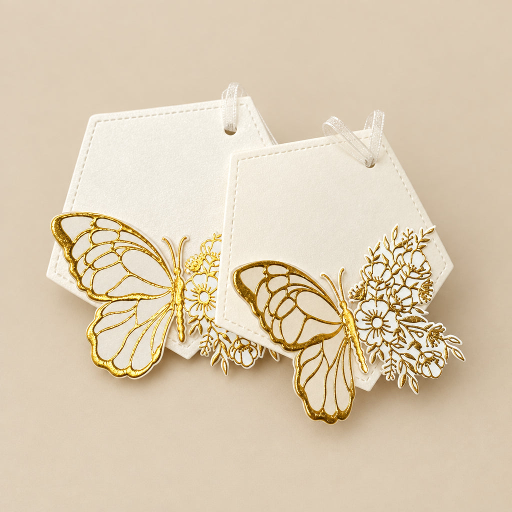 A set of white gift tags with gold foil-embossed butterfly designs, tied with a ribbon.